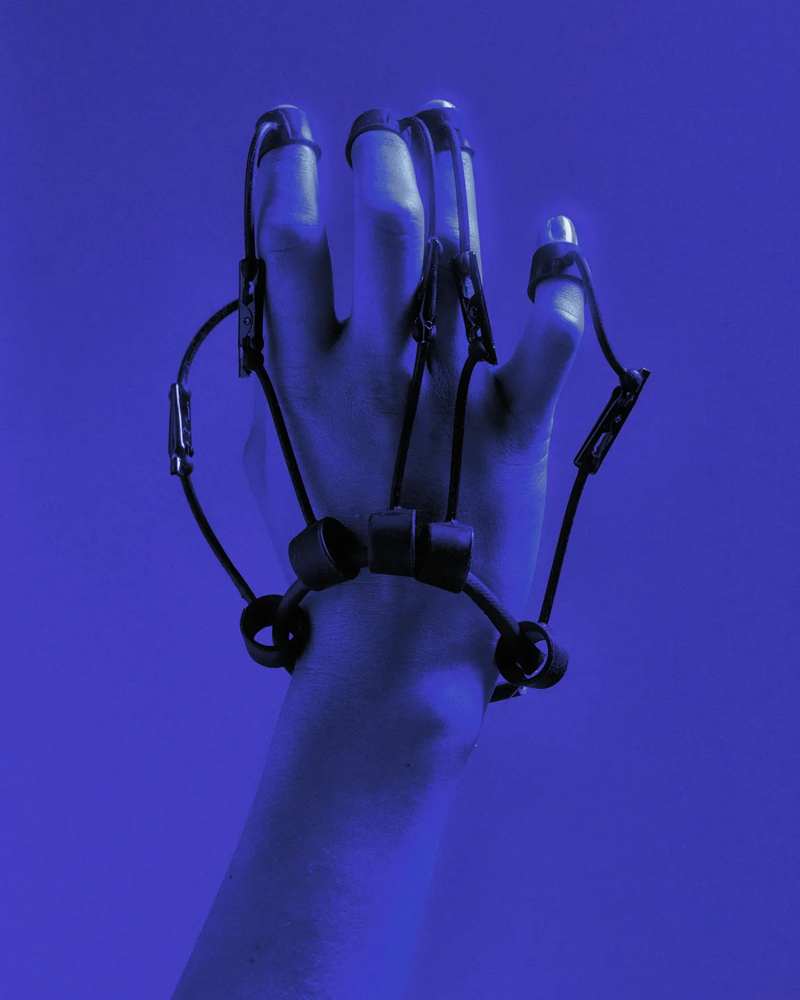 Hand wearing a wearable wired exoskeleton, deep blue tones